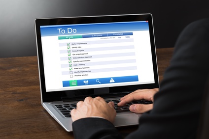 Close-up Of Businessperson Filling To Do List Form On Laptop At Desk